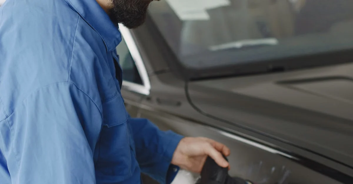 Technician machine-polishing a vehicle door