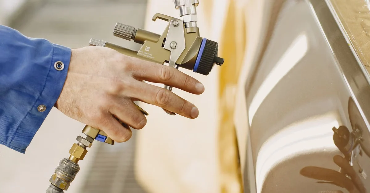 Technician applying automotive paint with a spray gun