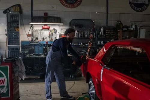 Body repair technician preparing a vehicle panel in a workshop